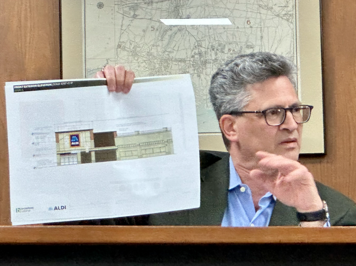 Great Neck Plaza Trustee Lawrence Katz holds up a facade rendering for the new Aldi coming to the village
